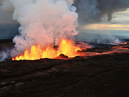 Lava shoots up high above a fissure in the ground.