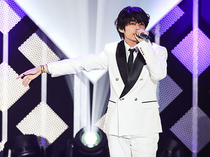 Kim Seok-Jin in a white suit performing on stage.